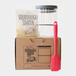 Sourdough starter kit with a glass jar, packaging, and red spatula on a white background