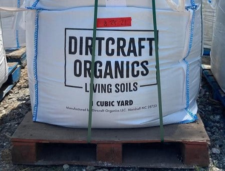 Large white bag labeled 'Dirtcraft Organics' on a wooden pallet.