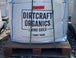 Large white bag labeled 'Dirtcraft Organics' on a wooden pallet.