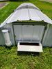Metal chicken coop with open door on grass