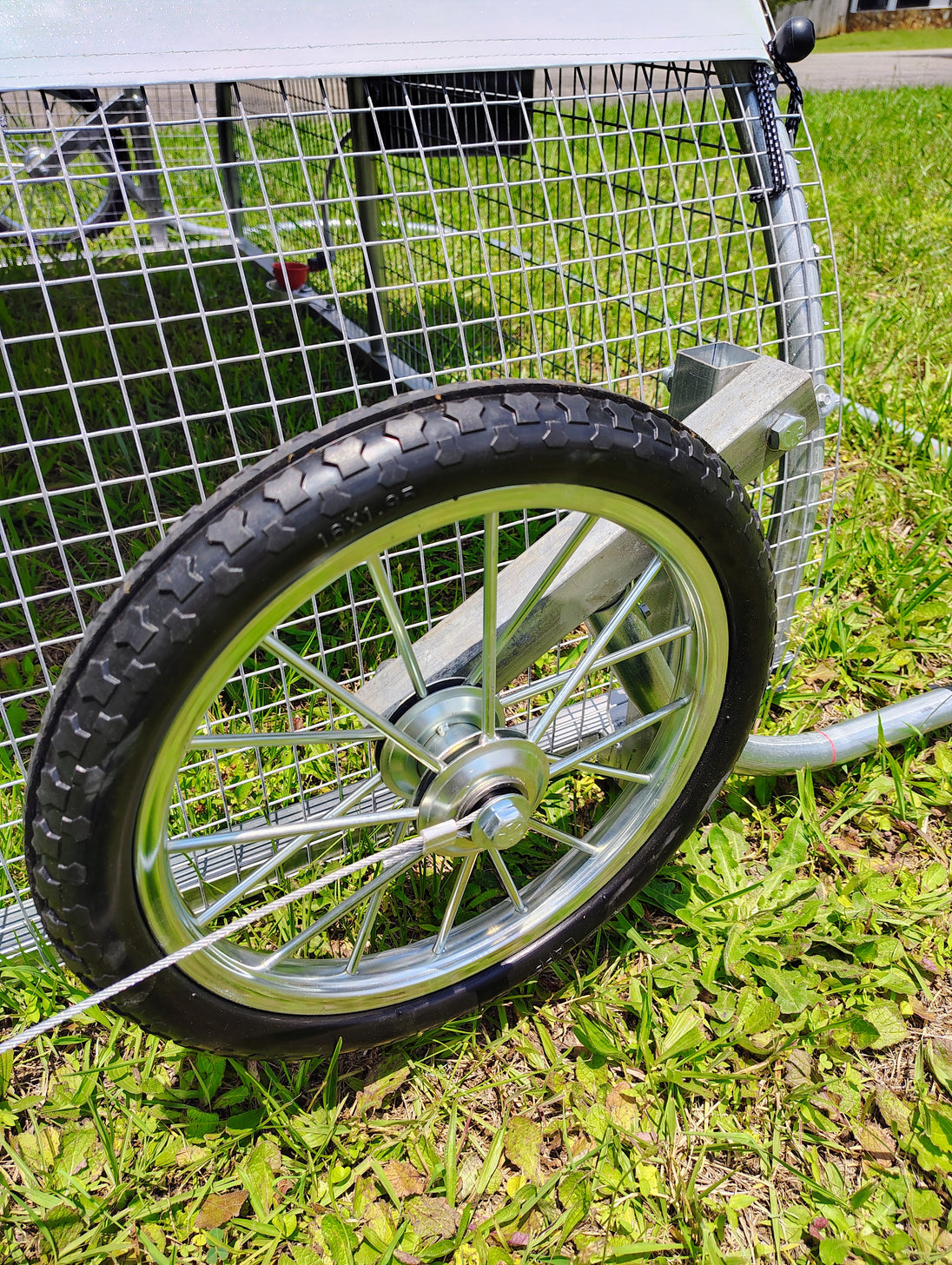 Close-up of a wheel on a metal frame with grass in the background