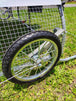 Close-up of a wheel on a metal frame with grass in the background