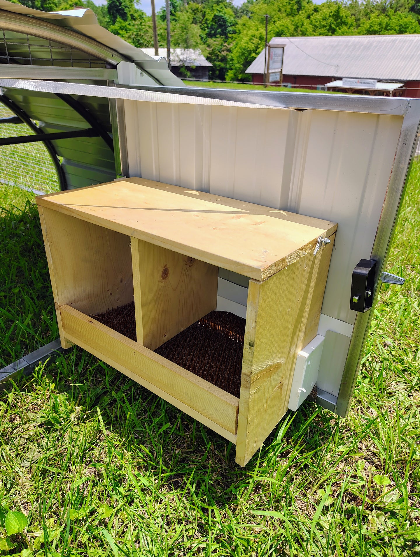Wooden chicken nesting boxes on portable chicken tractor coop with a metal roof and door